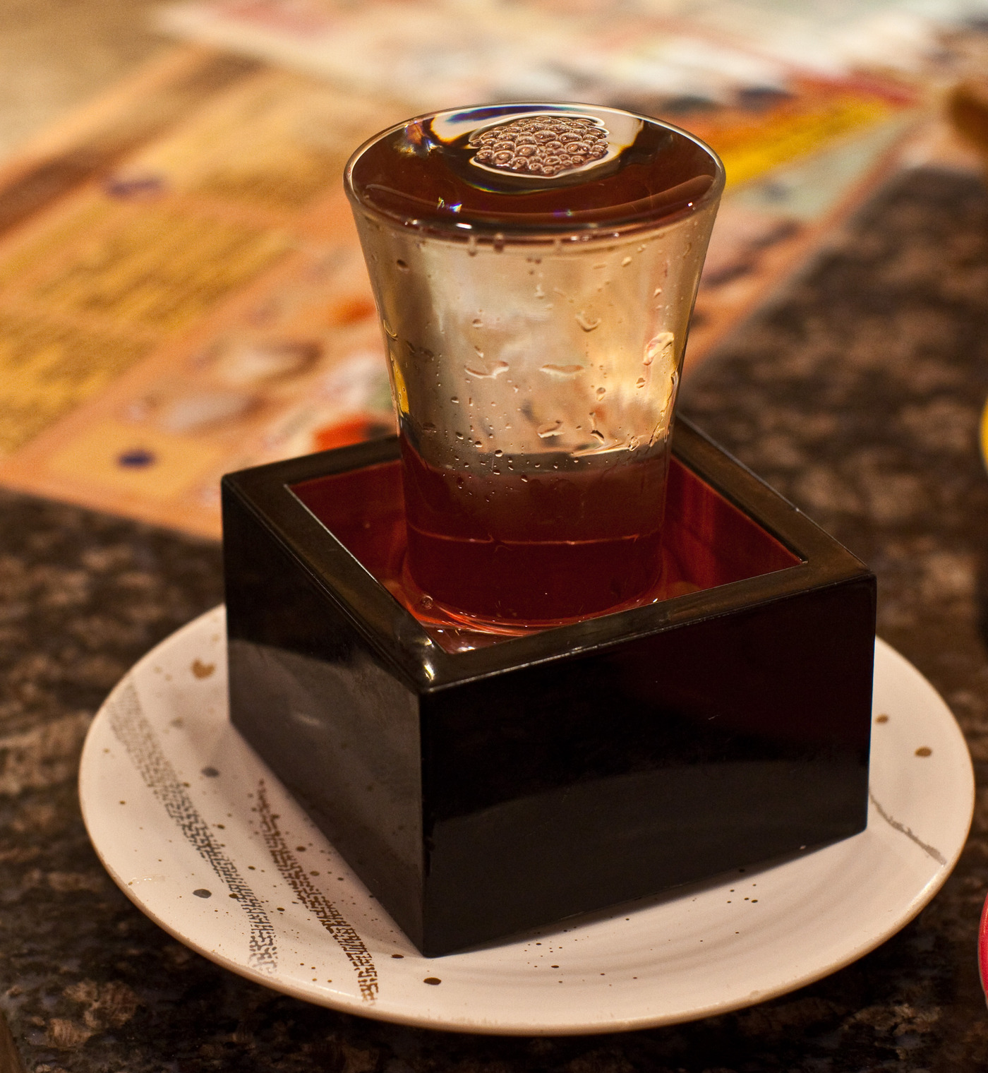 Саке. Один из вариантов подачи саке в японских барах. Рюмка наливается "с горкой"